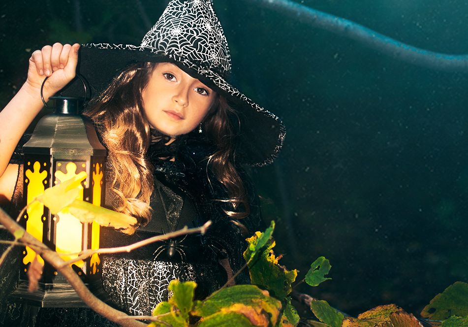 Girl in a halloween costume holding a lantern